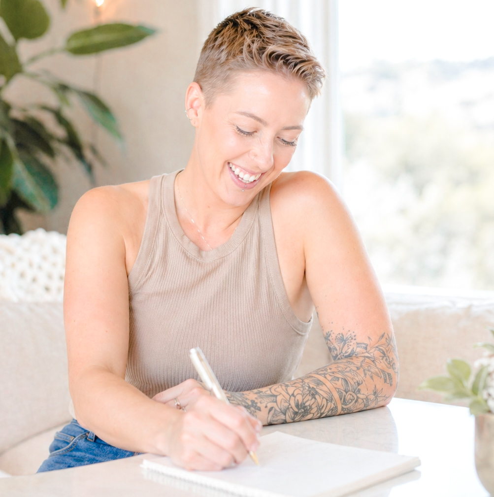 A short-haired woman sitting at a desk writing